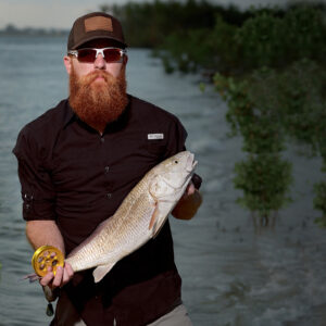 Guy holding a fish and a hand line fishing reel